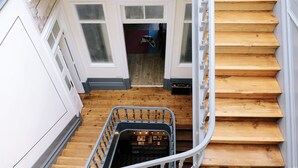 Un escalier en bois avec une rampe métallique et un petit chariot en bas.