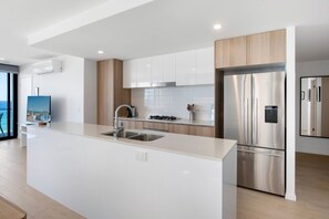 Una cocina moderna con una isla central, electrodomésticos de acero inoxidable y vistas al mar a través de un amplio ventanal.