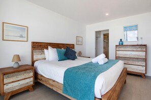 A neatly arranged bedroom with a wooden bed, a bedside table, a nightstand, and a dresser. - Ocean Views Apartment with Rooftop Pool (Palm Beach)