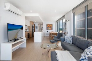 A modern living room with a flat-screen TV, a sofa, and a glass coffee table. - Ocean Views Apartment with Rooftop Pool (Palm Beach)