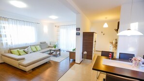 Een moderne woonkamer met een bank, salontafel en een eethoek met tafel en stoelen.