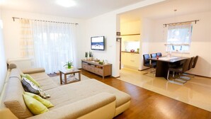 Een moderne woonkamer met een bank, salontafel en een eethoek met tafel en stoelen.