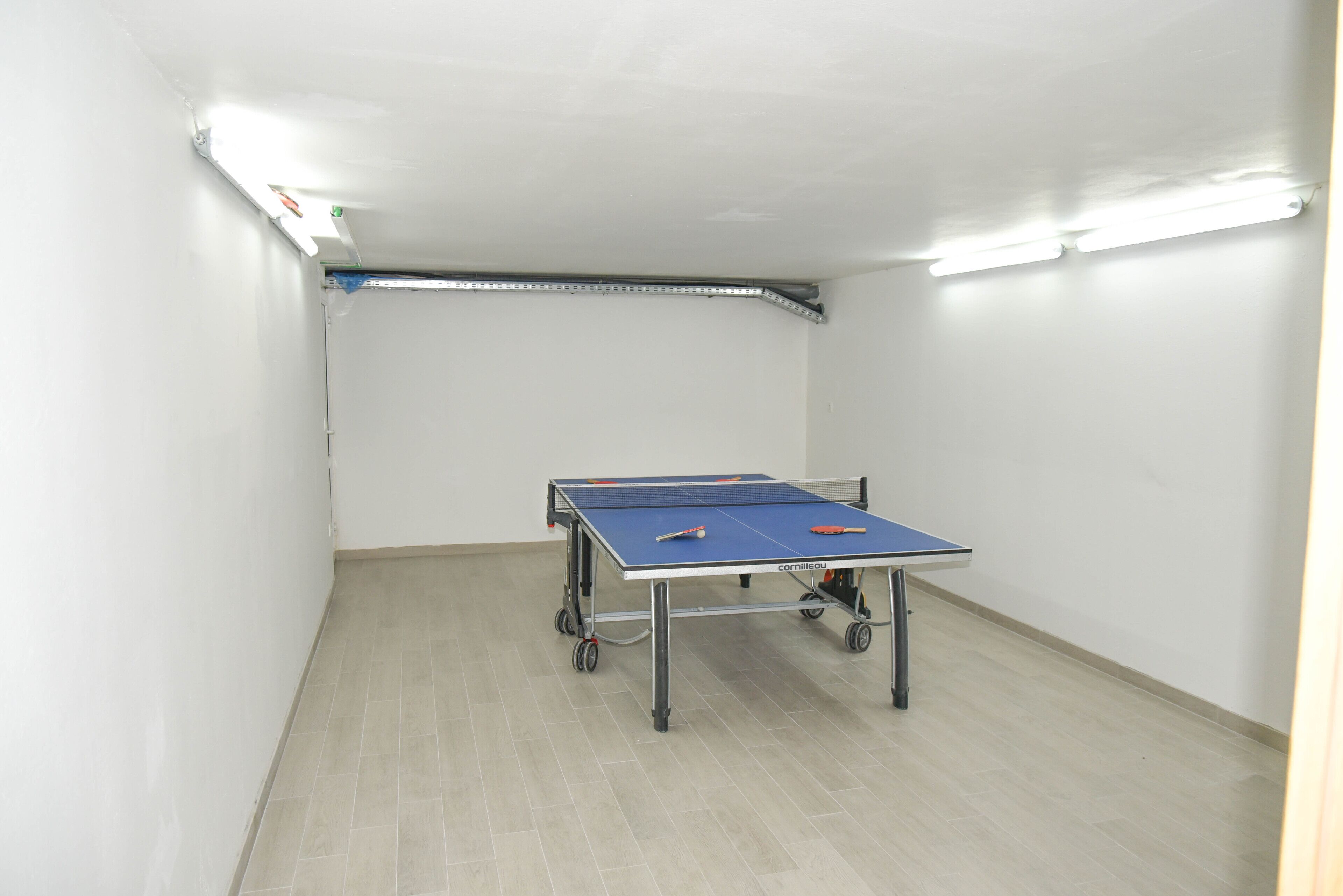 Ein Tischtennis-Tisch in einem Raum mit weißen Wänden und Fliesenboden.