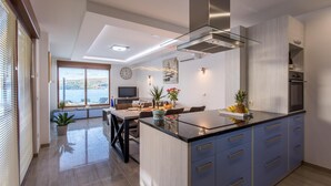 A modern kitchen with a central island, built-in appliances, and a dining area with a view. - Villa Ema with Seaview, swimming pool, garage, BBQ & playroom (Čižići (Krk))