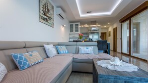 A modern living room with a sofa, coffee table, and a dining area. - Villa Ema with Seaview, swimming pool, garage, BBQ & playroom (Čižići (Krk))