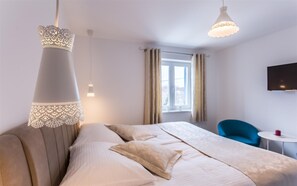 A modern hotel room with a large bed, two bedside lamps, a TV, and a small table with a red candle. - Villa Tana with a swimming pool, outdoor kitchen, BBQ & SUP (Sužan (Krk))