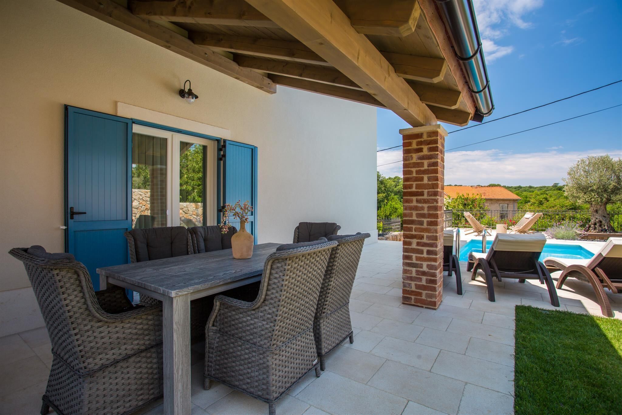 A patio with a table and chairs, a pool, and a blue door.