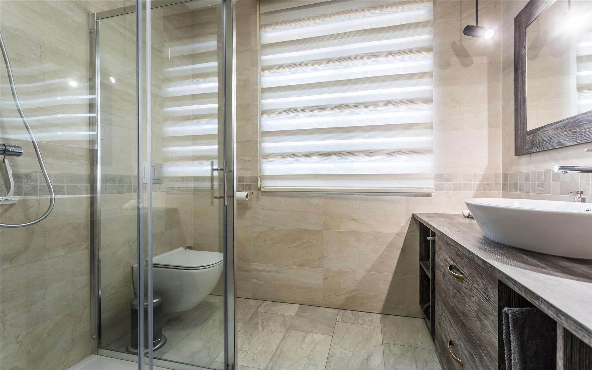 Ein modernes Badezimmer mit Duschkabine aus Glas, Toilette und Waschtisch.