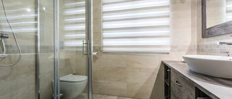 Ein modernes Badezimmer mit Duschkabine aus Glas, Toilette und Waschtisch.