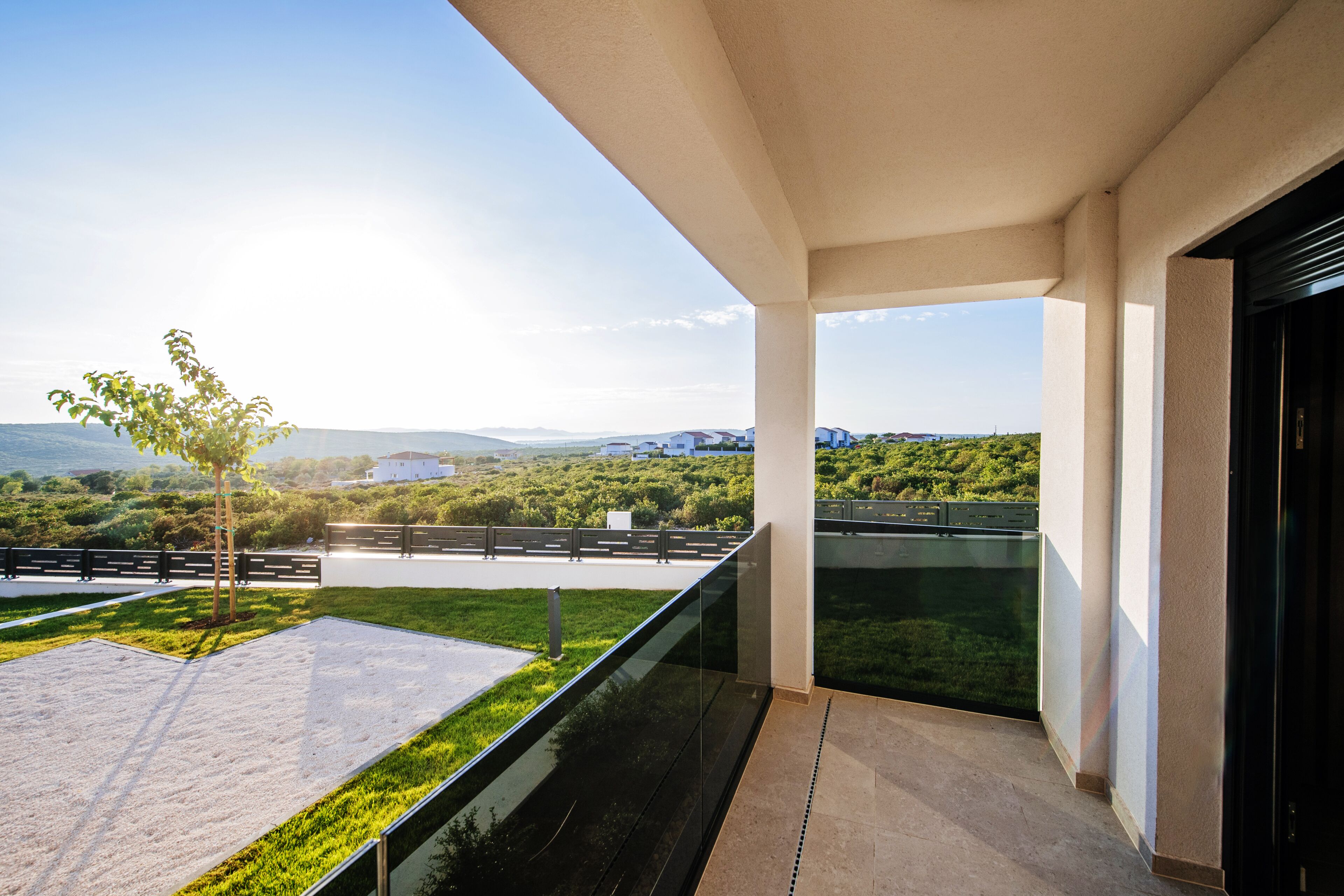 Ein Balkon mit Blick auf eine grüne Landschaft und ferne Hügel.