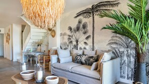 Un salon moderne avec un canapé, une table basse et une grande tapisserie murale.