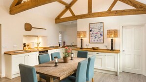 A kitchen with wooden beams, a dining table with chairs, and a white door.