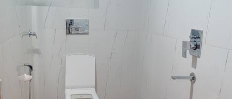 A bathroom with a toilet, shower, and sink.