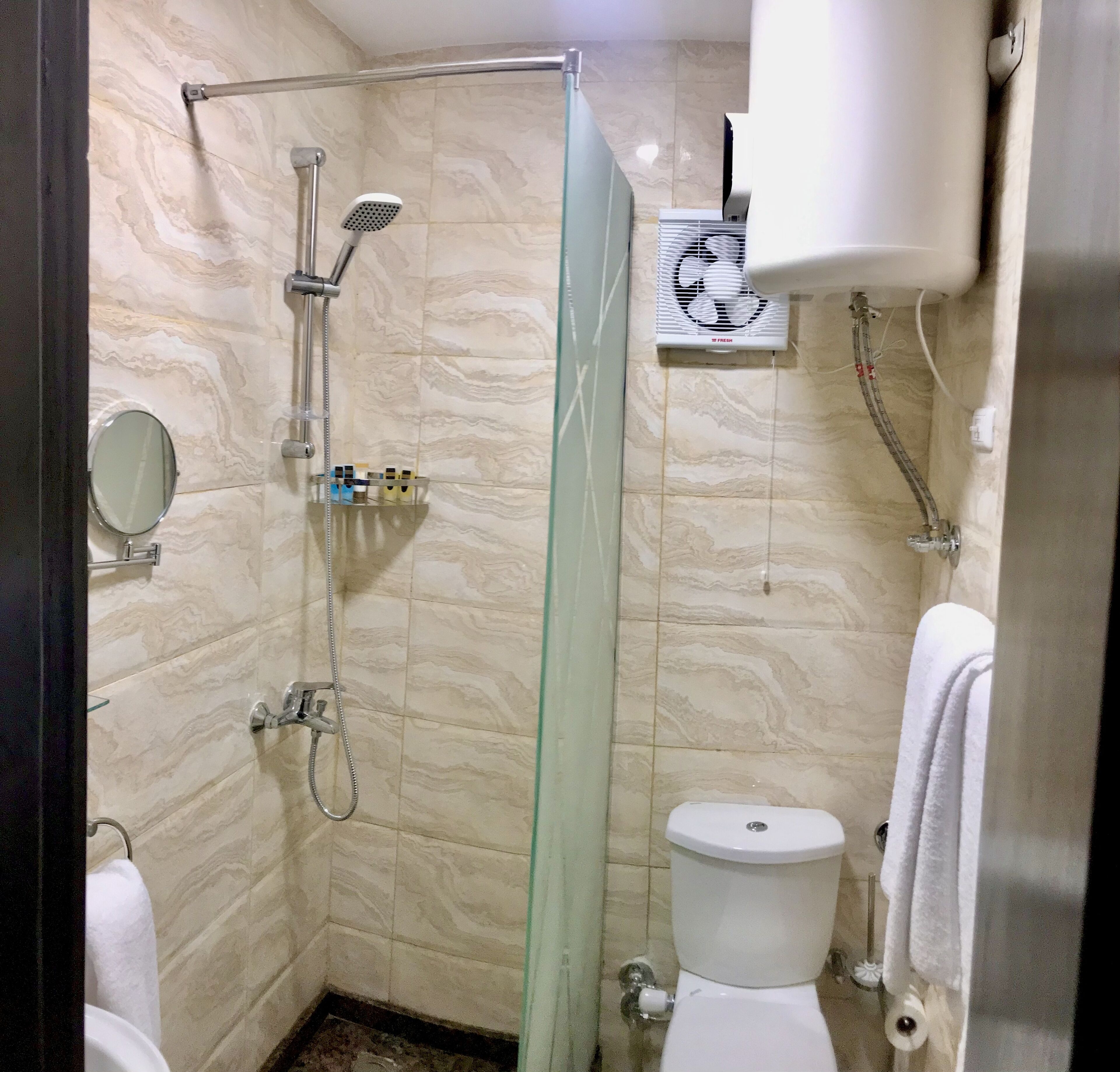 A bathroom with a glass shower enclosure, a toilet, and a towel rack.