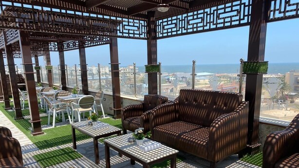 A rooftop terrace with outdoor furniture, a pergola, and a view of the cityscape. - Jewel Port Said Hotel (Port Said)