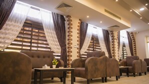 A seating area with cushioned chairs, a small table with a vase, and a brick accent wall. - Jewel Port Said Hotel (Port Said)