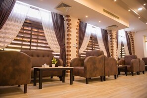 A hotel lobby with a row of sofas, a coffee table with a flower, and a brick accent wall. - Jewel Port Said Hotel (Port Said)