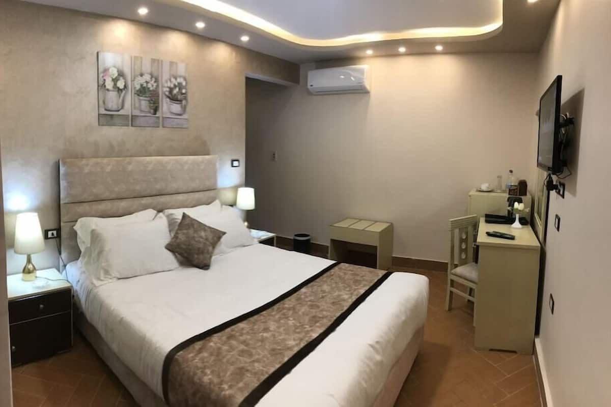 A bedroom with a bed, nightstands, a desk, and a chair.