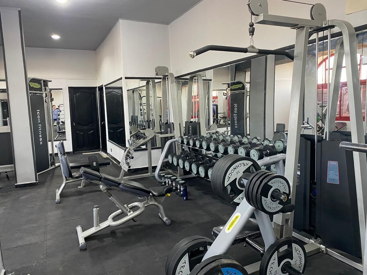 Un gimnasio con diverso equipo de ejercicio, incluyendo mancuernas, bancos y máquinas de pesas.
