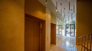 A modern interior with a polished floor, a wooden elevator, and a staircase with metal railings. - Central Chic Apartments (Tirana)