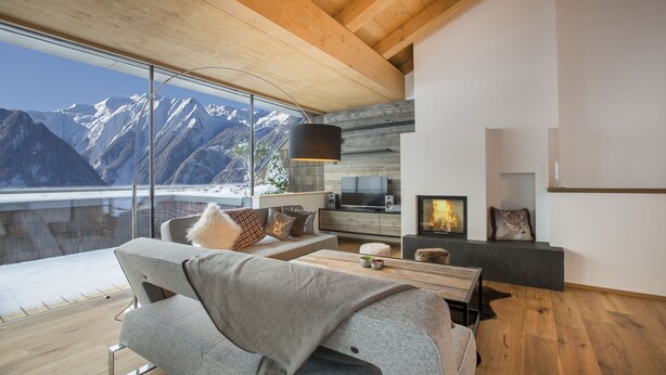 Una sala de estar moderna con un amplio ventanal con vistas a una montaña nevada.