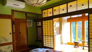 A traditional Japanese room with tatami flooring, a sliding door, and a bed with patterned bedding.