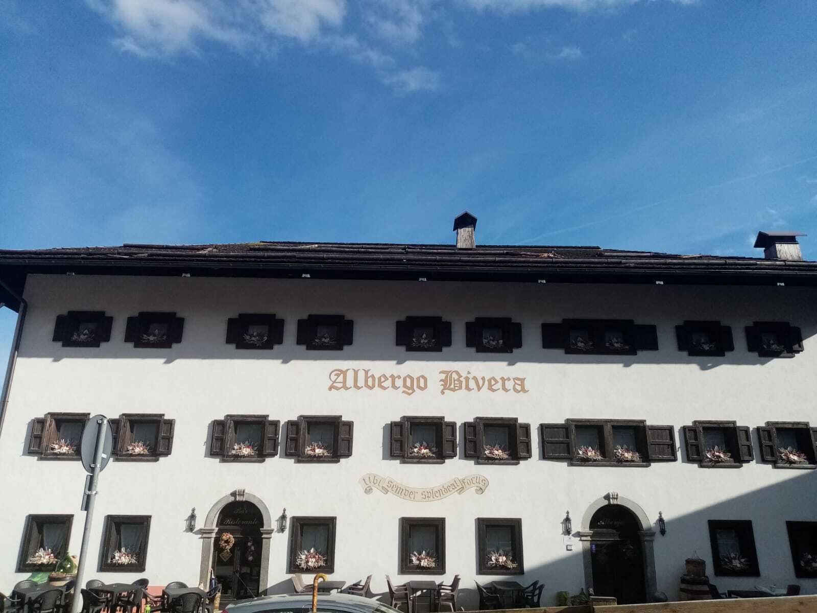 Ein Gebäude mit der Aufschrift "Albergo Riviera" an der Fassade, das zahlreiche Fenster mit Blumenarrangements und einen klassischen Baustil aufweist.