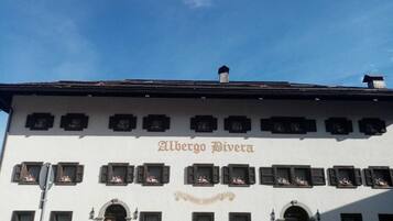 Ein Gebäude mit der Aufschrift "Albergo Riviera" an der Fassade, das zahlreiche Fenster mit Blumenarrangements und einen klassischen Baustil aufweist.