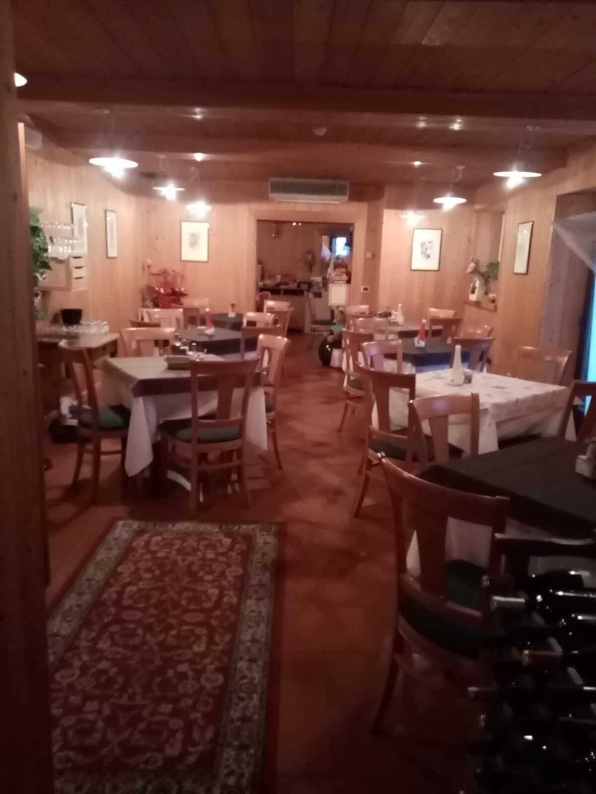 Tunnelmallinen ravintola, jossa on puuseinät ja -pöydät, kuvioitu matto ja seinillä tauluja.