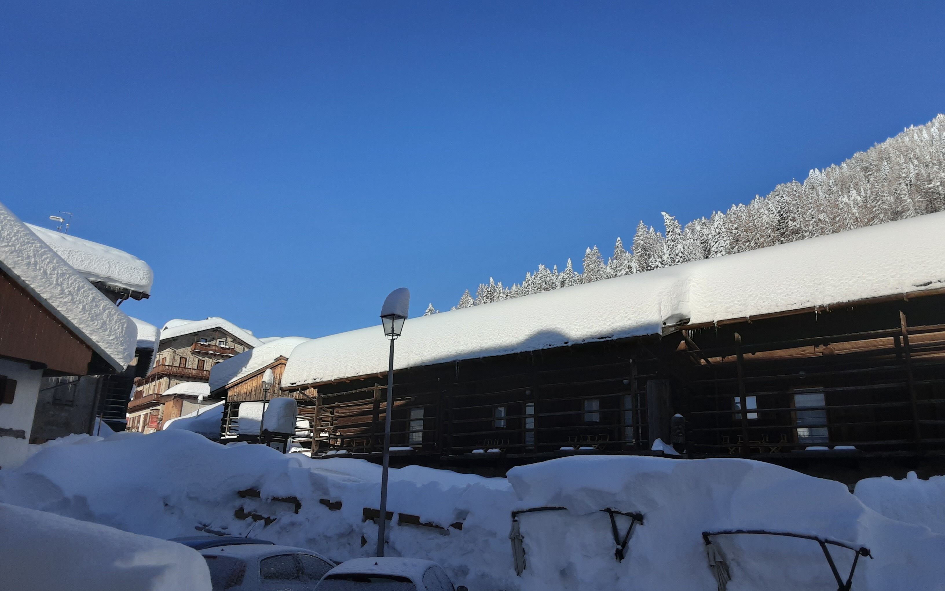 A snowy village with wooden buildings and snow-covered trees.