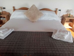 A neatly made bed with a patterned bedspread, a fluffy pillow, and folded towels on the side. - Hotel Bivera Sauris (Sauris)