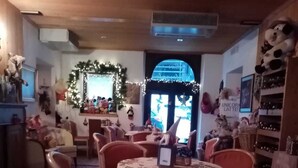 A cozy restaurant with round tables and red chairs, decorated with Christmas lights and a Christmas tree. - Hotel Bivera Sauris (Sauris)