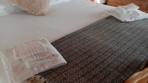 A neatly made bed with white linens, a beige throw pillow, and a patterned throw blanket. - Hotel Bivera Sauris (Sauris)