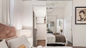 Un dormitorio con cama, mesita de noche, lámpara, armario y un cuadro enmarcado en la pared.
