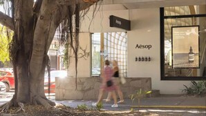Un edificio con un letrero que dice 'Aesop' y un amplio ventanal que muestra un producto.