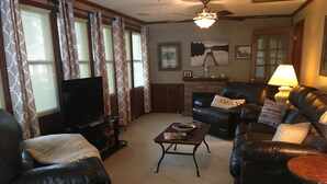 Ein Wohnzimmer mit Fernseher, Ledersofas, einem Couchtisch und einem Kamin.