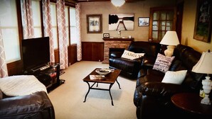 Ein Wohnzimmer mit Kamin, Ledersofas, einem Couchtisch und einem Fernseher.
