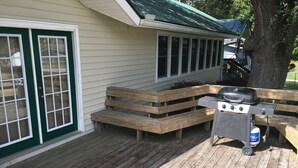 Eine Holzterrasse mit Grill und Sitzbank.