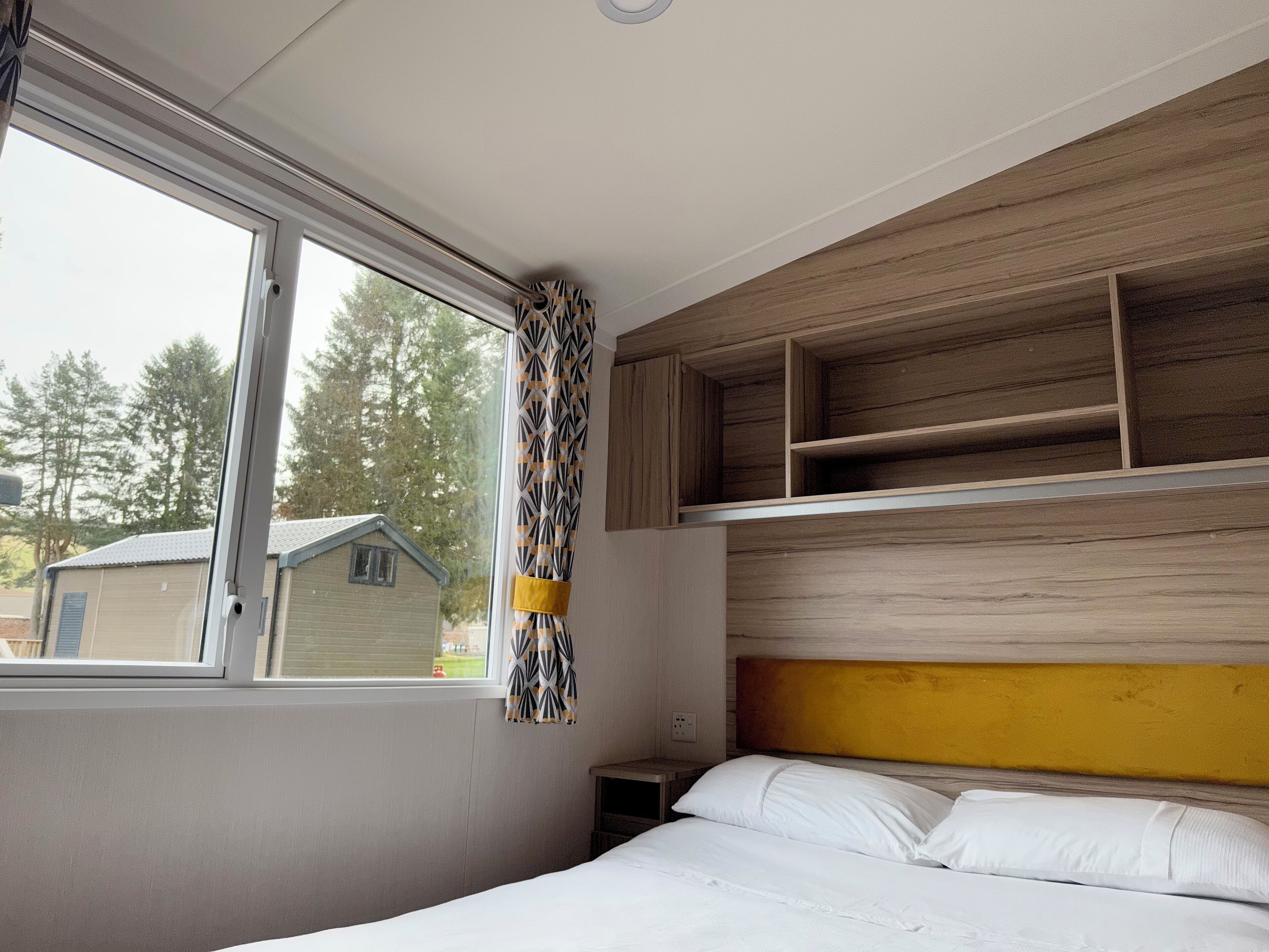 A bedroom with a bed, a window, and built-in wooden shelves.