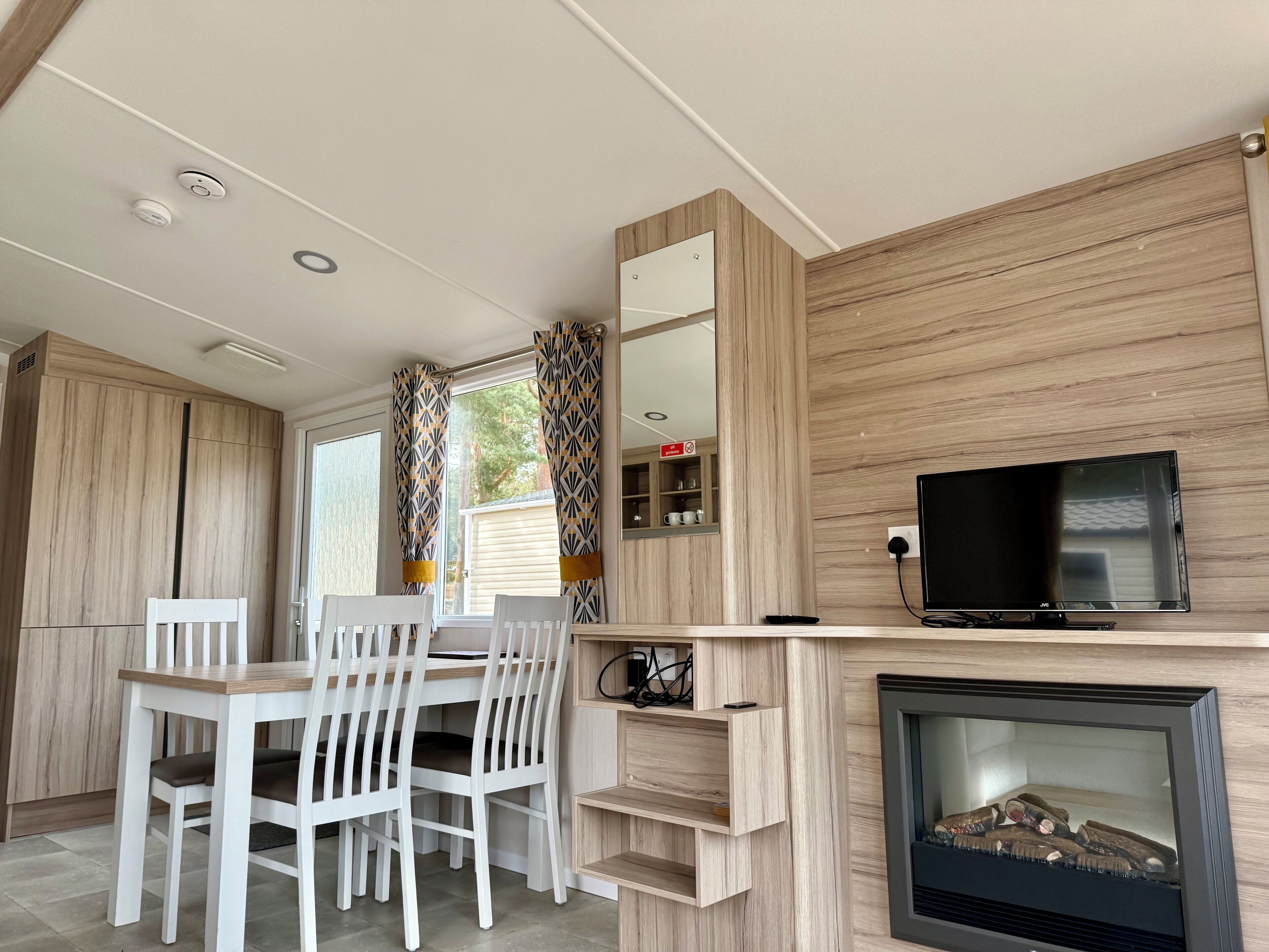 Una cucina moderna con zona pranzo, mobili in legno, una TV a schermo piatto e un camino.