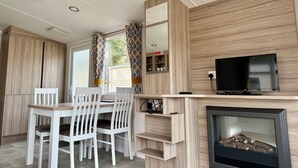 Una cucina moderna con zona pranzo, mobili in legno, una TV a schermo piatto e un camino.