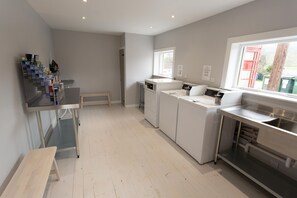 Laundry room with stainless steel sink, washing machine, and drying rack.