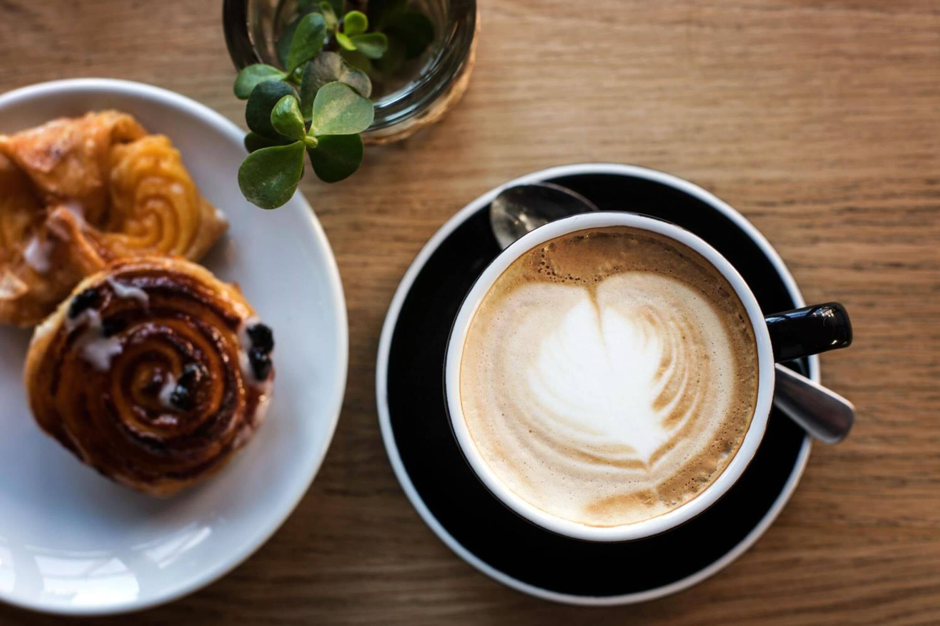 A plate with pastries and a cup of coffee on a wooden table.