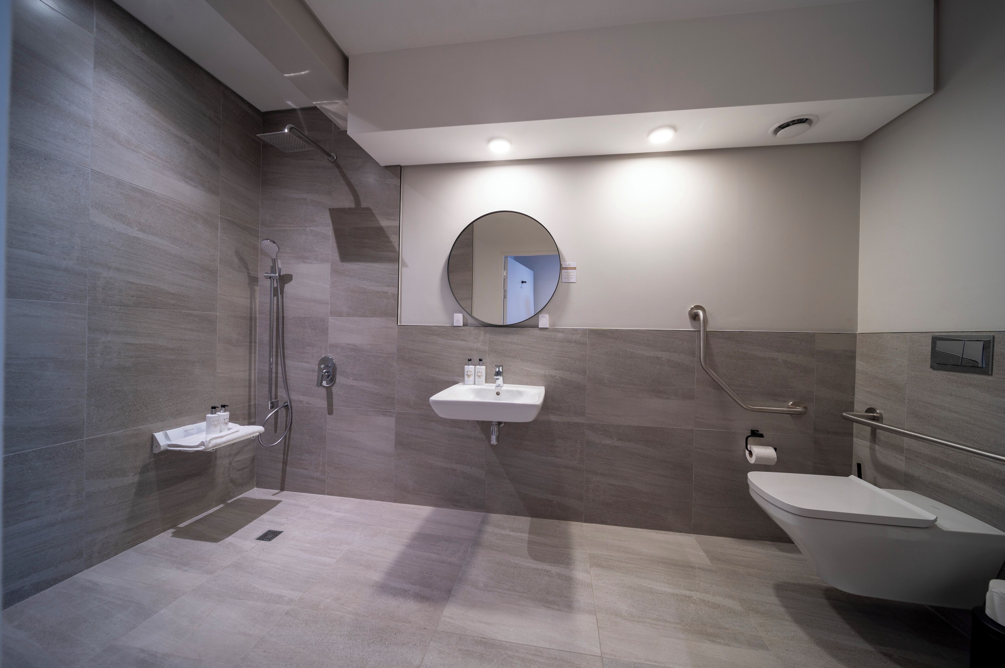 A modern bathroom with a shower, sink, and toilet.