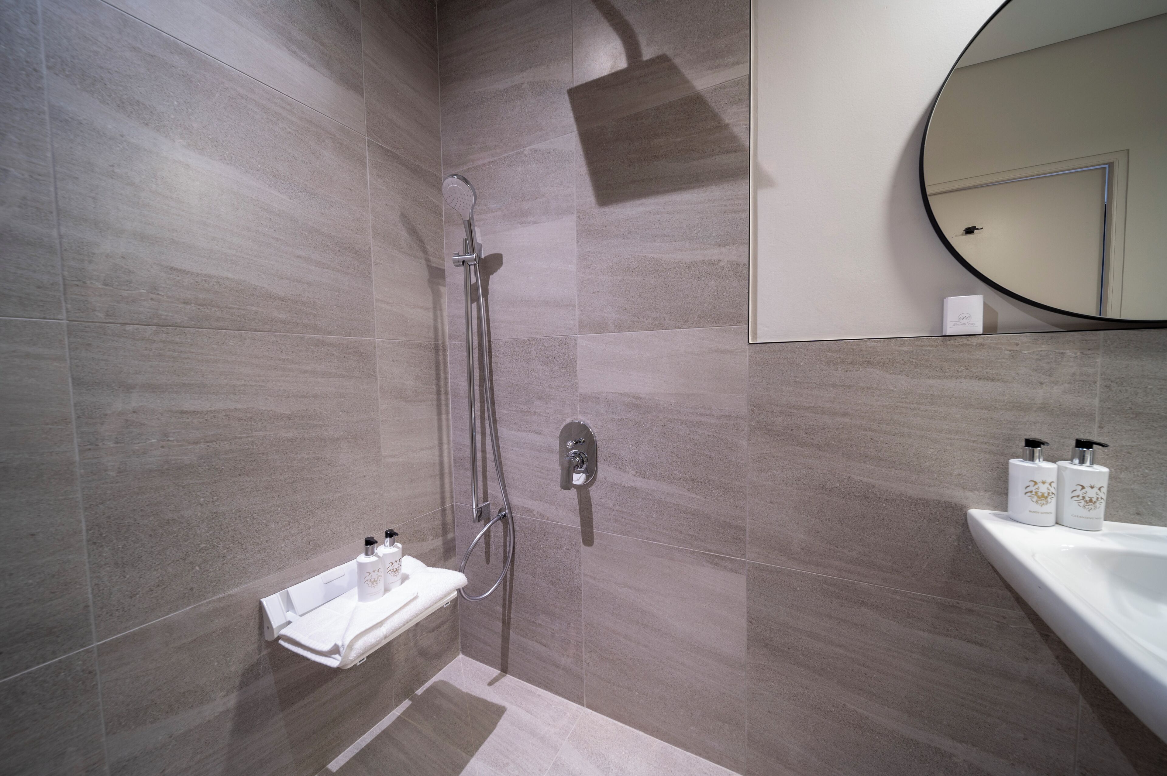 Une salle de bain moderne avec une douche, un lavabo et un miroir.