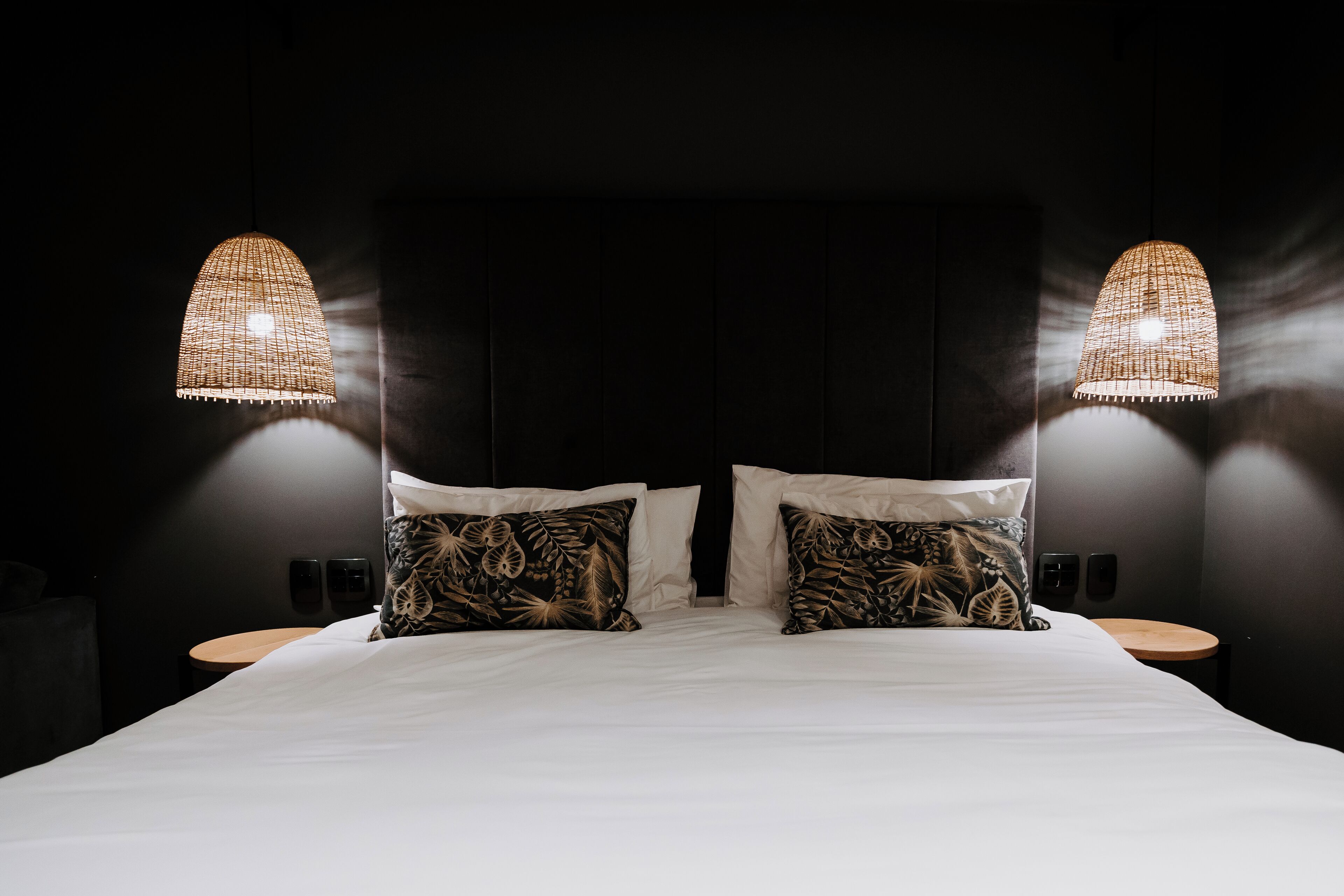 A hotel room with a large bed, two bedside tables, and two wall-mounted lamps.