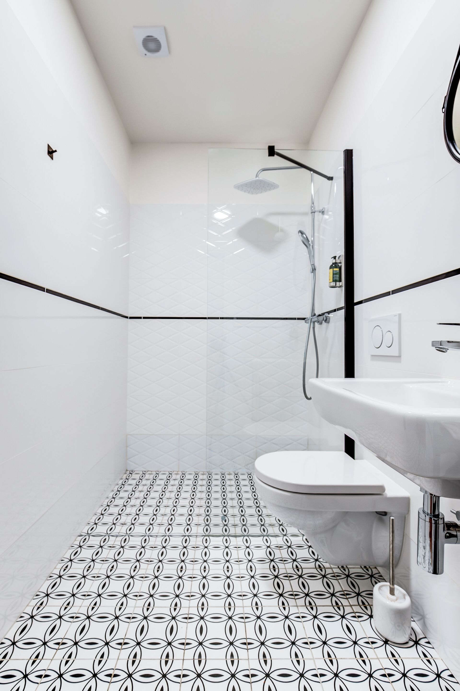 Un bagno moderno con pavimento decorato, un water, un lavandino e una doccia.