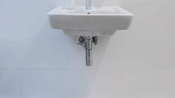 Une salle de bain avec un lavabo blanc, un miroir rond et des carreaux de sol à motifs.