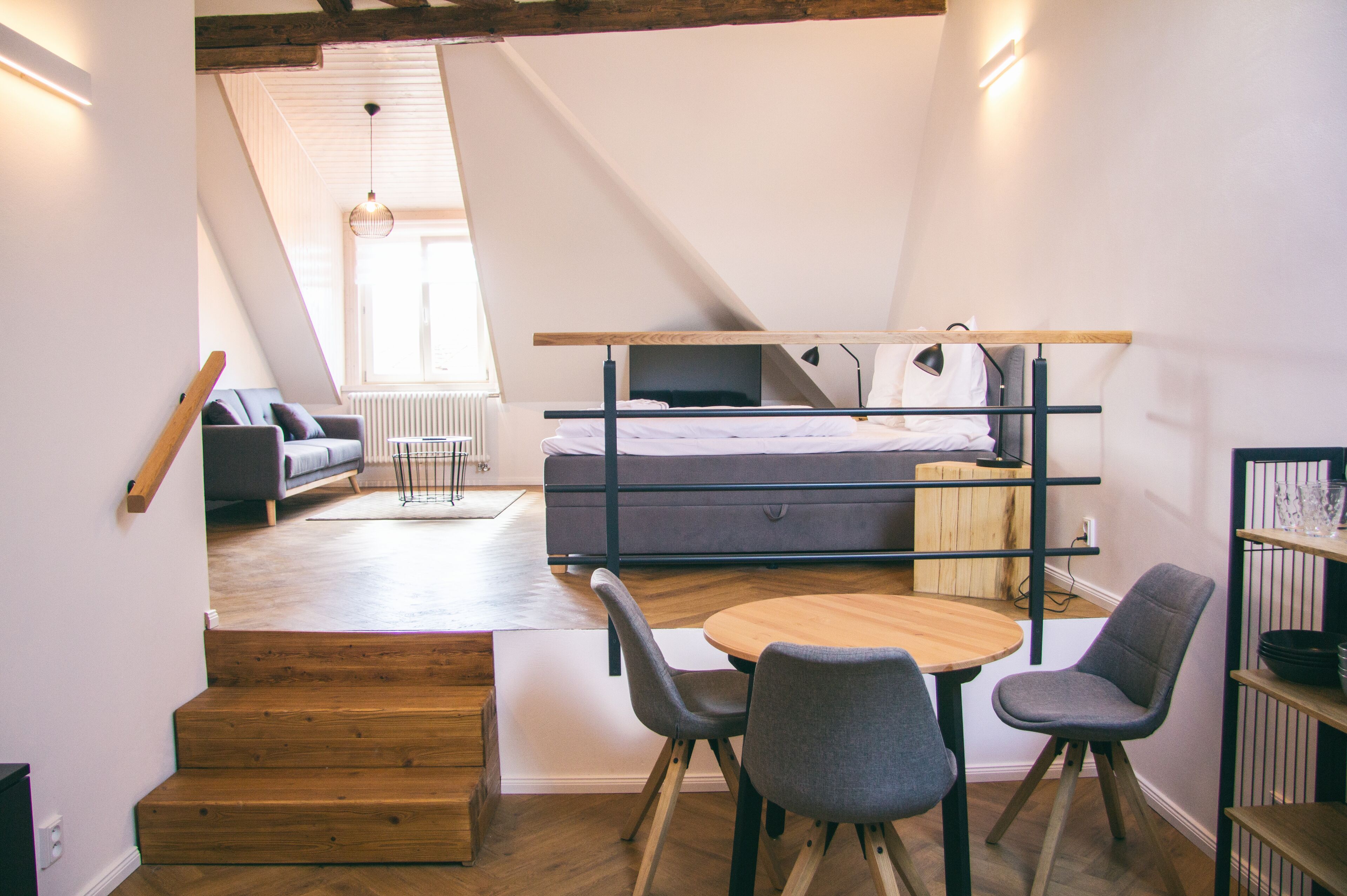 Un dormitorio estilo loft con cama, sofá y zona de comedor con sillas.