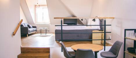 Un dormitorio estilo loft con cama, sofá y zona de comedor con sillas.